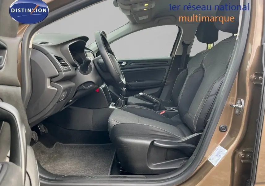 Vue intérieure côté conducteur de la Renault Mégane IV brun cappuccino, montrant les sièges tissu et la boîte manuelle.