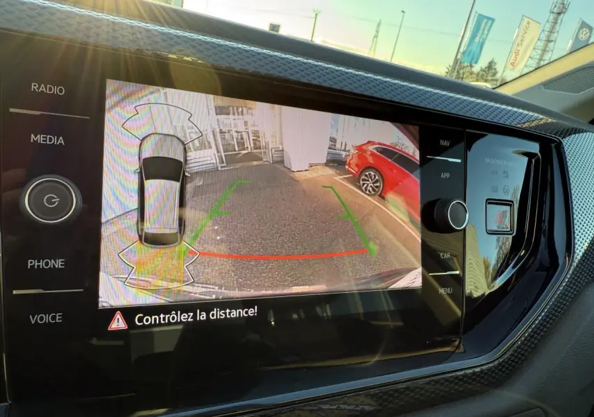 Écran de caméra de recul dans un Volkswagen Taigo 2025, vue arrière avec véhicule rouge à droite.