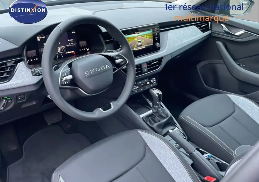Vue intérieure côté conducteur du Skoda Kamiq 2025 avec tableau de bord moderne et sellerie tissu gris et noir.