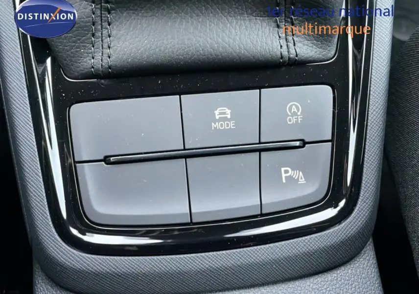 Gros plan sur la console centrale du Skoda Kamiq gris graphite, montrant les boutons de mode de conduite et assistance au stationnement.