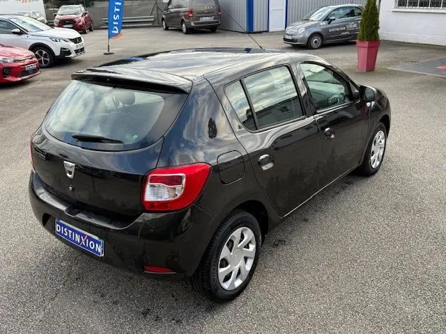 Vue 3/4 arrière droite d'une Dacia Sandero noire de 2015, avec cinq portes et jantes argentées, stationnée en extérieur.
