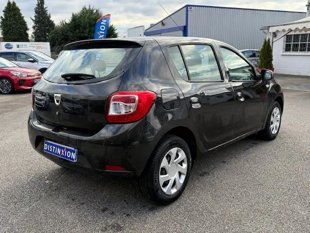 Vue 3/4 arrière droite d'une Dacia Sandero noire 2015, cinq portes, avec jantes acier et feux arrière visibles.
