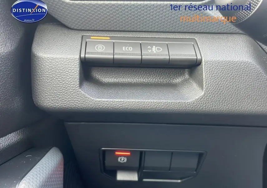 Gros plan sur les commandes de tableau de bord noir du Dacia Duster vert cèdre, avec bouton Eco et frein à main électrique.