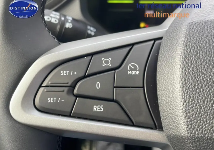 Gros plan sur les commandes multifonctions noires du volant côté gauche du Dacia Duster 2026 vert cèdre.