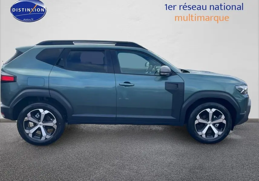 Vue latérale droite d'un Dacia Duster 2026 vert cèdre avec jantes alliage et barres de toit visibles.