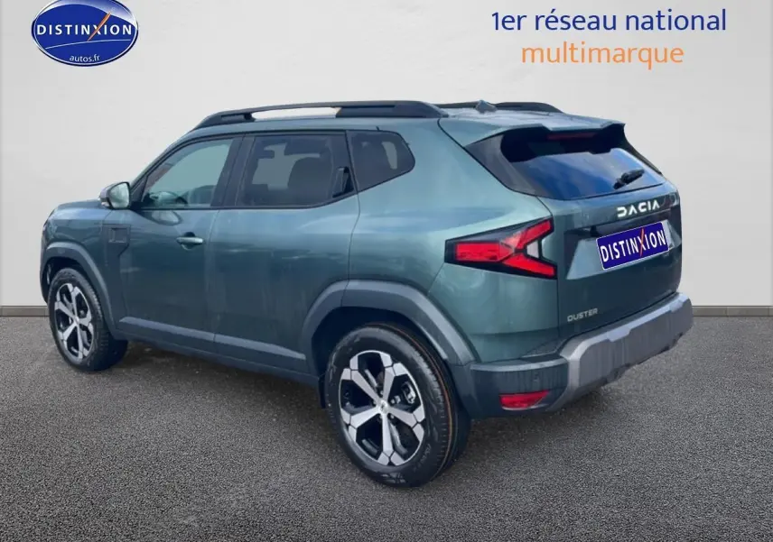 Vue 3/4 arrière droite d'un Dacia Duster vert cèdre avec barres de toit et jantes alu modernes.