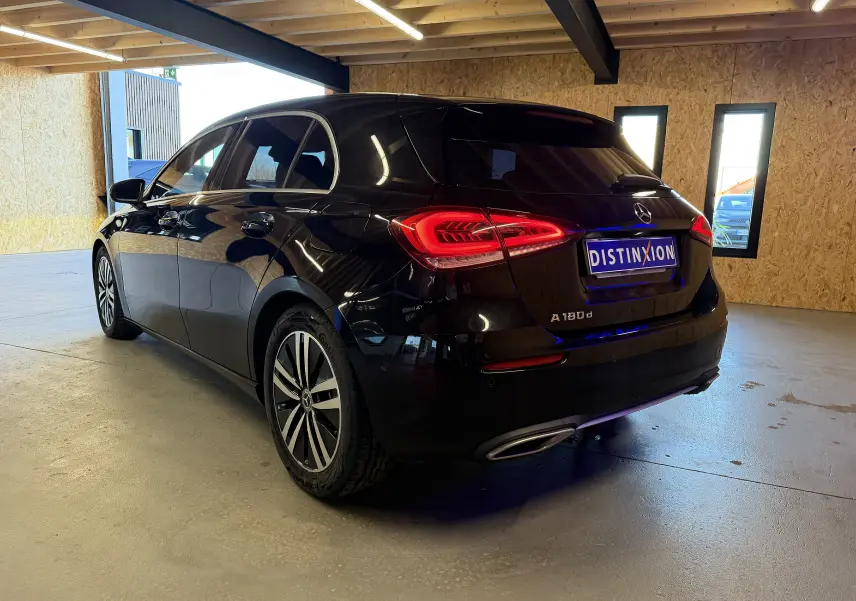 Vue 3/4 arrière droite d'une Mercedes Classe A noire avec feux LED allumés et jantes alliage dans un garage.