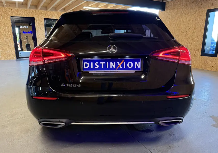 Vue arrière d'une Mercedes Classe A noire avec feux LED et double sorties d'échappement chromées dans un garage.