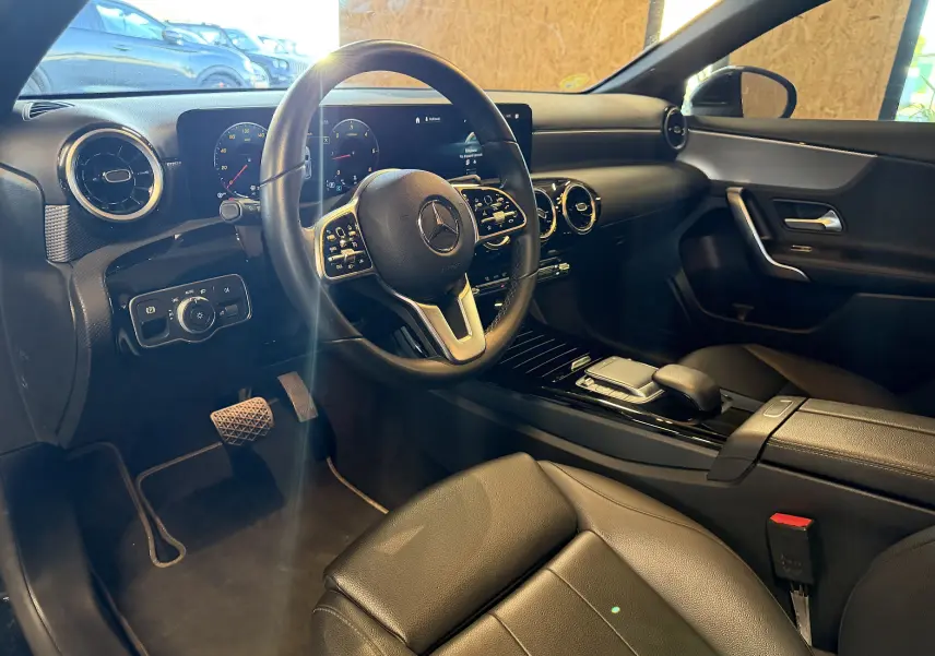 Vue intérieure côté conducteur de la Mercedes Classe A 2022 noire, avec volant cuir multifonctions et tableau de bord digital.