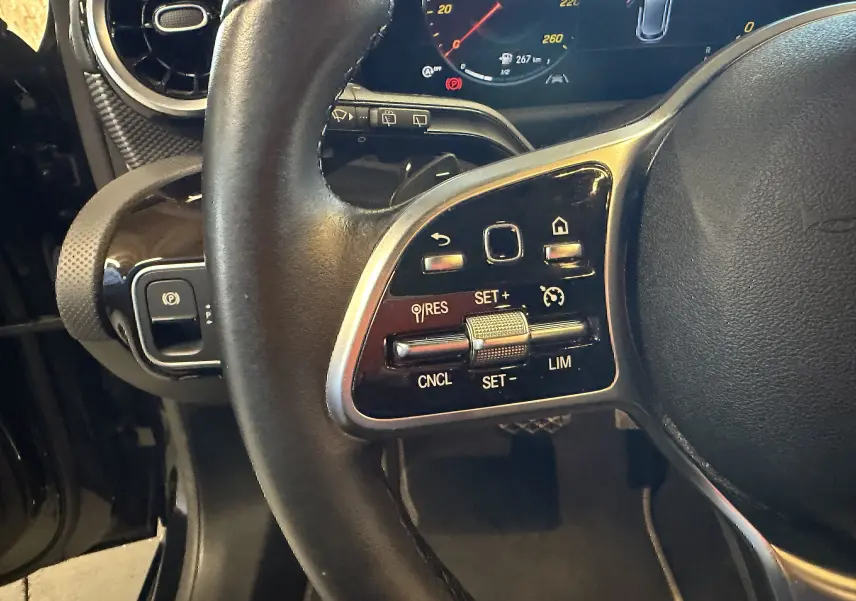 Gros plan sur le volant cuir noir multifonctions côté gauche de la Mercedes Classe A 2022 avec commandes de régulateur de vitesse.