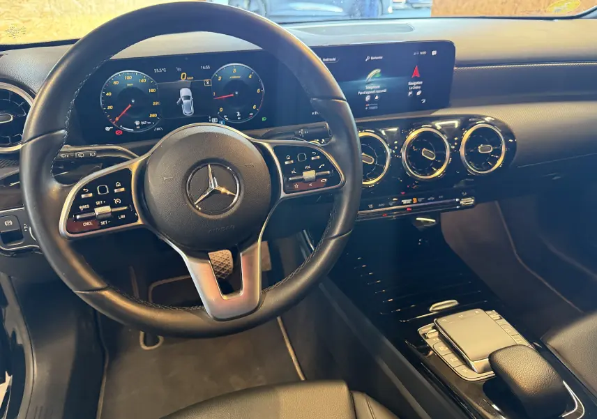 Vue intérieure du poste de conduite noir de la Mercedes Classe A 2022 avec volant cuir multifonctions et écran tactile large.