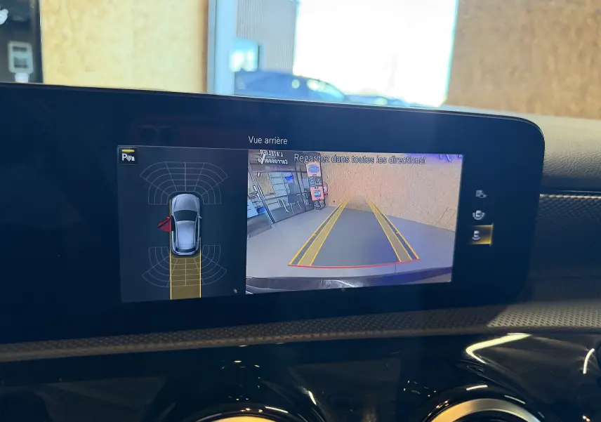 Écran tactile intérieur d'une Mercedes Classe A noire 2022 montrant la caméra de recul et l'aide au stationnement.