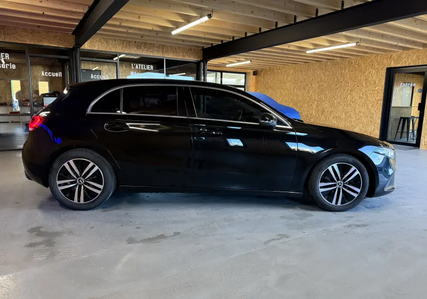Vue de profil côté gauche d'une Mercedes Classe A noire avec jantes alliage et vitres teintées dans un garage.