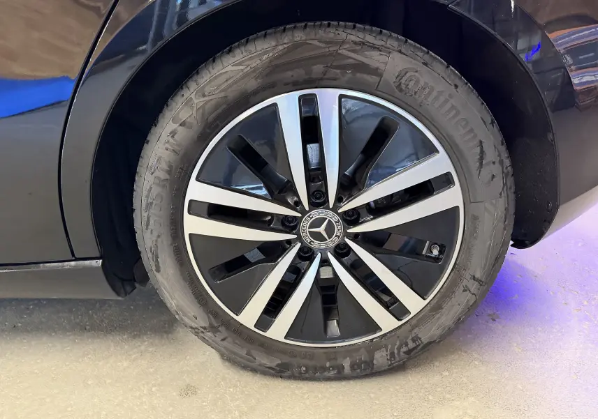 Gros plan sur la jante alu bicolore noire et argentée du côté gauche d'une Mercedes Classe A noire.