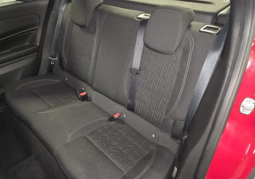Vue intérieure de la banquette arrière noire avec motifs FIAT, ceintures et portière rouge visible côté droit.