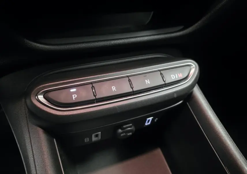 Gros plan sur la console centrale noire avec les boutons de la boîte auto et ports USB visibles d'une Fiat 600 rouge.