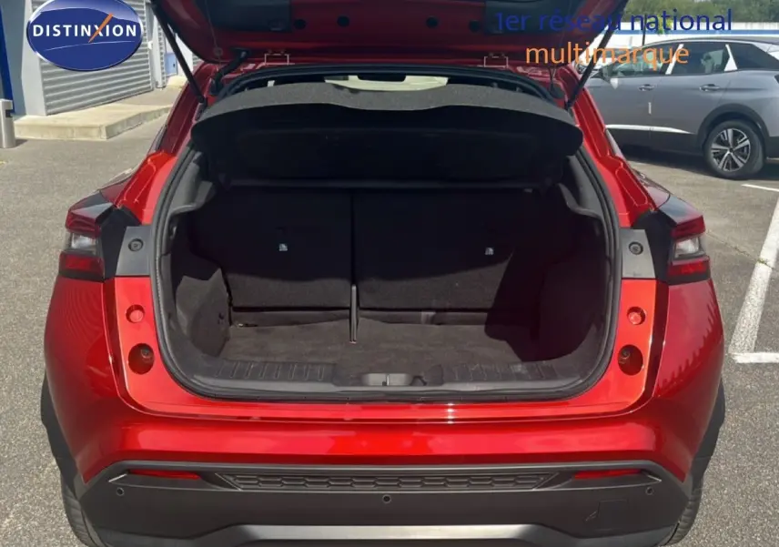 Vue arrière du Nissan Juke rouge Fuji Metal 2024 avec coffre ouvert montrant l'espace de chargement vide.