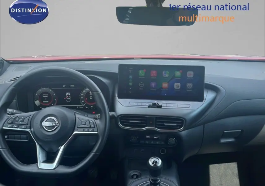 Vue intérieure du tableau de bord du Nissan Juke rouge Fuji Metal 2024, avec écran tactile et boîte manuelle.