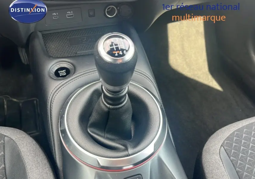 Le levier de vitesse manuel en gros plan dans l'habitacle noir du Nissan Juke rouge Fuji Metal 2024.