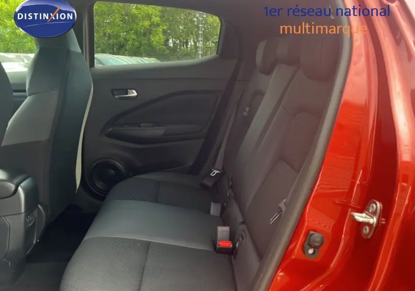 Vue intérieure côté droit sur les sièges arrière noirs du Nissan Juke 2024 rouge Fuji Metal avec porte ouverte.