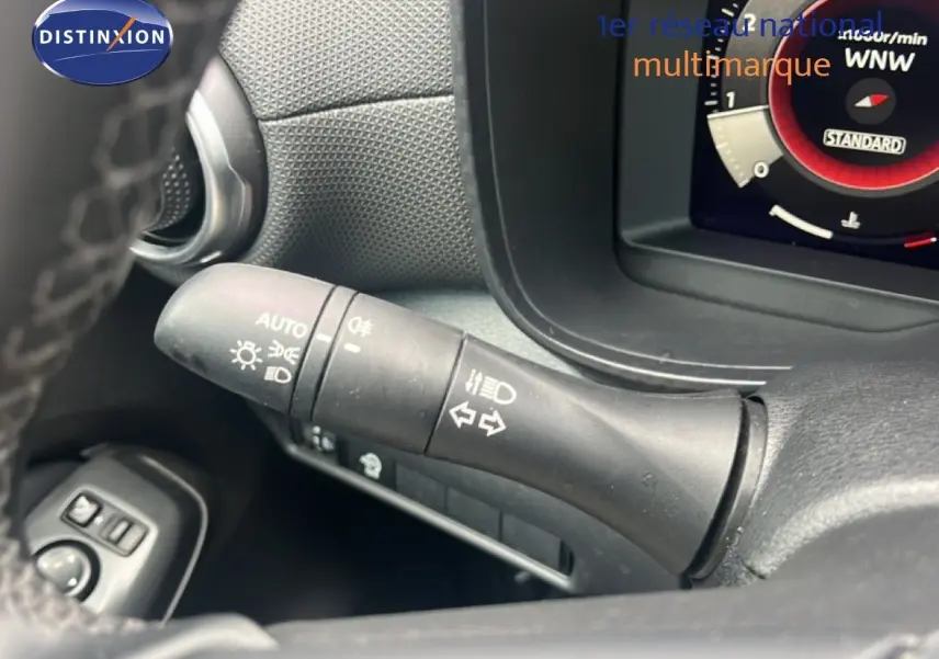 Gros plan sur la commande des feux et clignotants dans l’habitacle du Nissan Juke rouge Fuji Metal 2024.