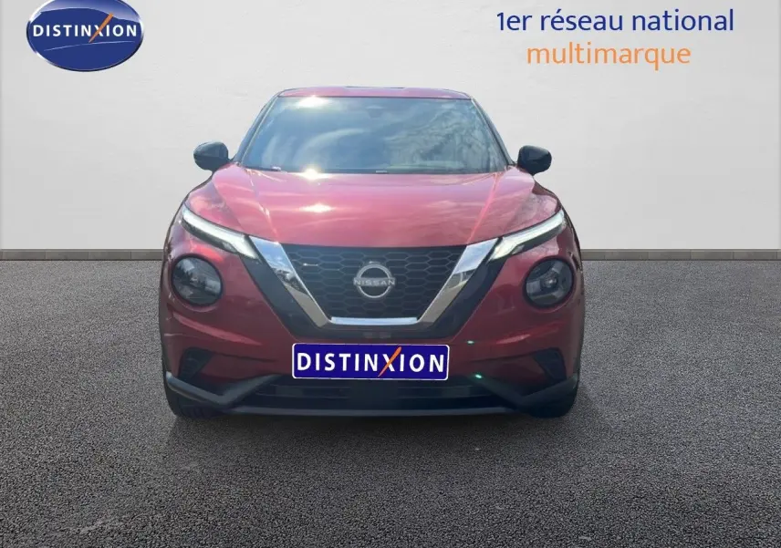 Vue frontale d'un Nissan Juke 2024 rouge Fuji Metal avec calandre en V chromée et phares ronds distinctifs.