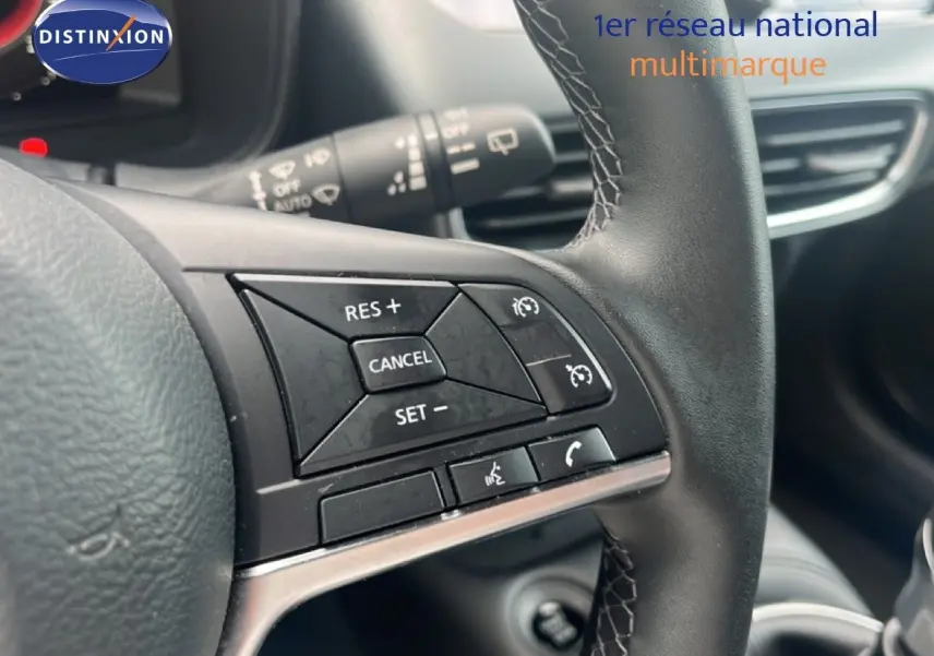 Gros plan sur les commandes de régulateur de vitesse au volant en cuir noir du Nissan Juke rouge Fuji Metal 2024.