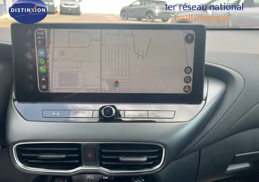 Vue rapprochée de la console centrale du Nissan Juke 2024 rouge Fuji Metal, avec écran tactile et commandes de climatisation.