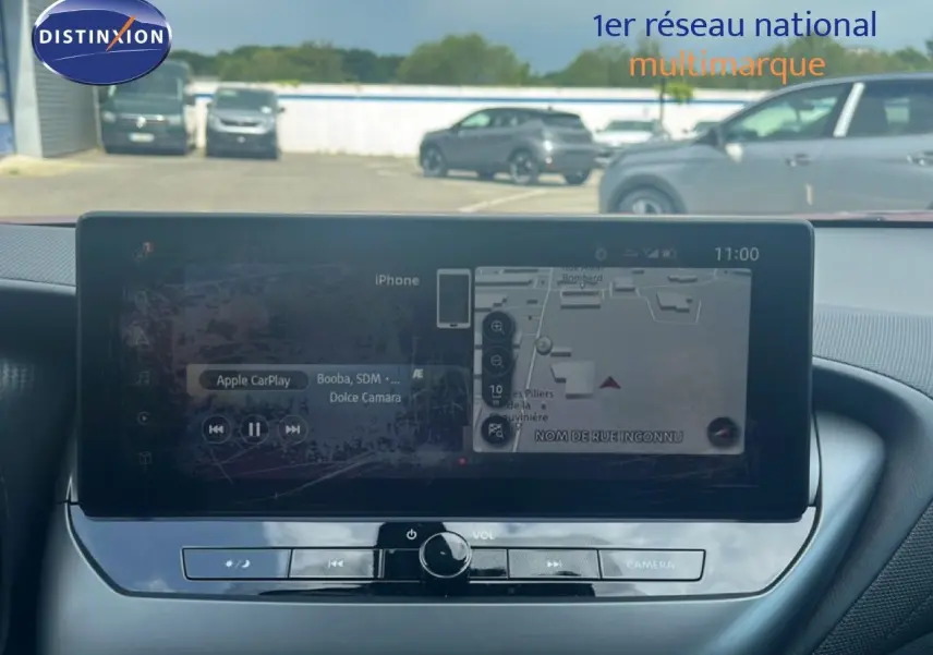 Écran tactile central du Nissan Juke rouge Fuji Metal 2024, affichant navigation et Apple CarPlay, vue intérieure frontale.