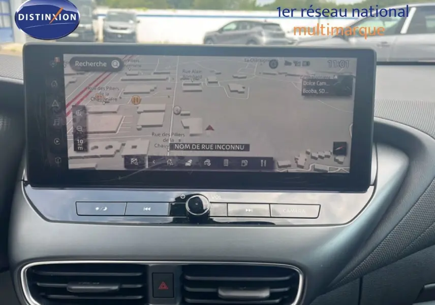 Écran tactile central du Nissan Juke 2024 rouge Fuji Metal, affichant la navigation GPS avec commandes intégrées.