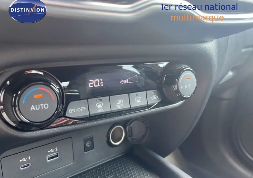 Détail de la console centrale du Nissan Juke rouge Fuji Metal 2024, montrant les commandes de climatisation et ports USB.