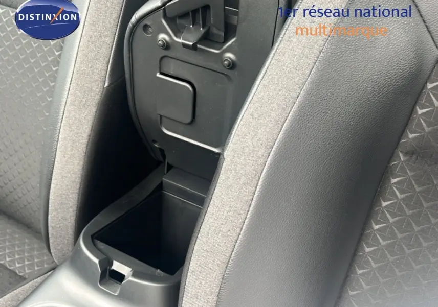 Gros plan sur la console centrale ouverte entre les sièges avant en tissu gris du Nissan Juke 2024.