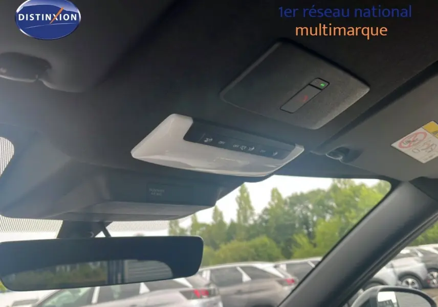 Vue intérieure du toit et rétroviseur d’un Nissan Juke 2024 rouge Fuji Metal, avec commandes au plafond visibles.