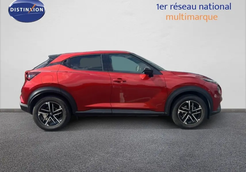 Profil côté gauche du Nissan Juke 2024 rouge Fuji Metal avec jantes alliage noires et toit noir contrasté.