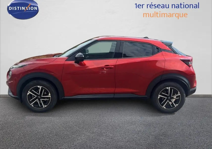 Profil droit d'un Nissan Juke 2024 rouge Fuji Metal avec jantes alliage noires et toit légèrement surélevé.