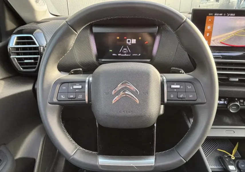 Vue rapprochée du volant cuir noir de la Citroën C4 2024 avec commandes intégrées et tableau de bord numérique.