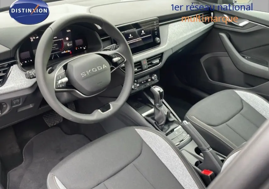 Intérieur du Skoda Kamiq 2025 en tissu noir et gris, vue côté conducteur sur le tableau de bord et la console centrale.