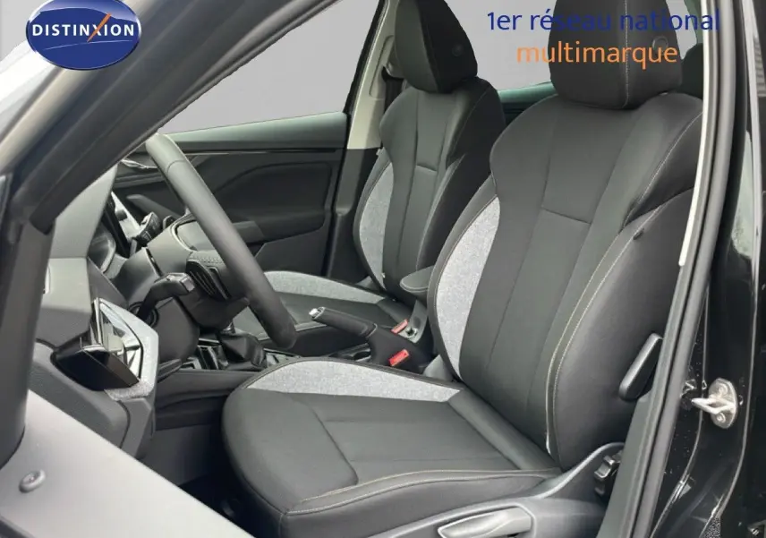 Vue intérieure côté conducteur du Skoda Kamiq 2025 noir, mettant en valeur les sièges tissu bicolores gris et noir avec coutures contrastées.