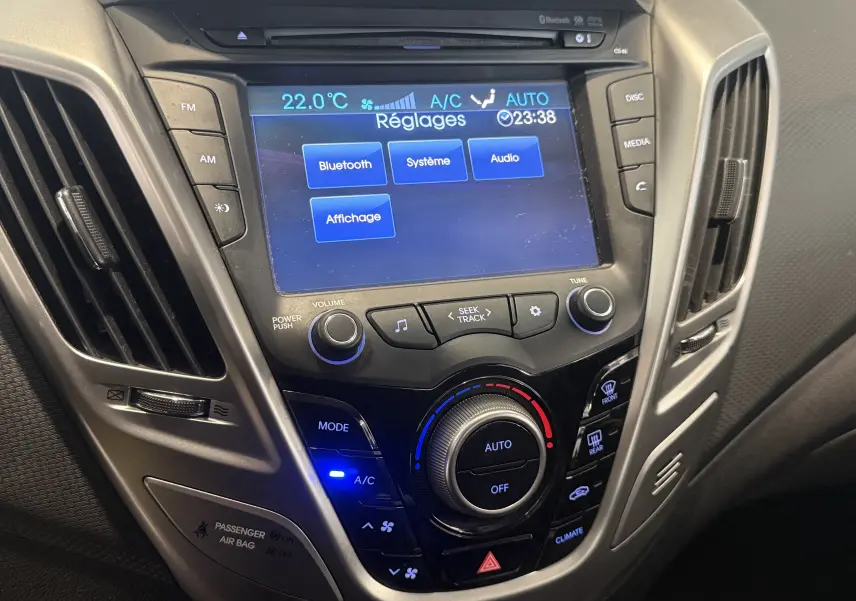 Vue rapprochée du tableau de bord de la Hyundai Veloster 2025, avec écran tactile et commandes climatisation éclairées.