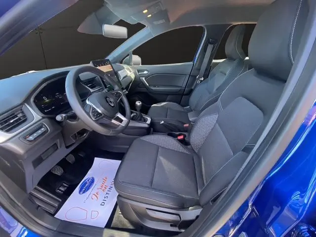 Vue intérieure côté conducteur du Renault Captur 2024 bleuiron, montrant sièges tissu et volant manuel en tissu.