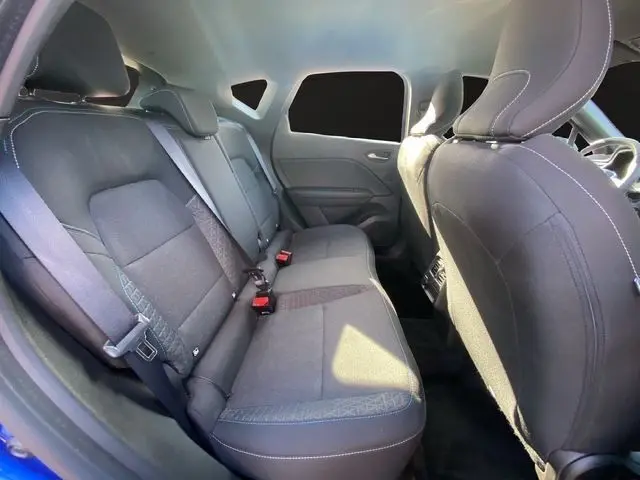 Vue intérieure arrière côté gauche du Renault Captur 2024 bleuiron, montrant la banquette tissu et les appuie-têtes.