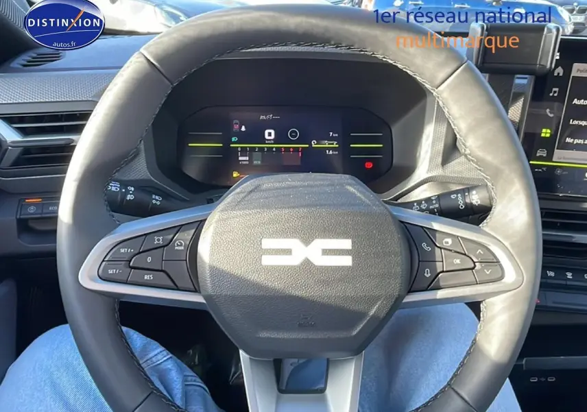 Vue intérieure centrée sur le volant multifonction noir du Dacia Duster 2026 avec tableau de bord numérique en arrière-plan.