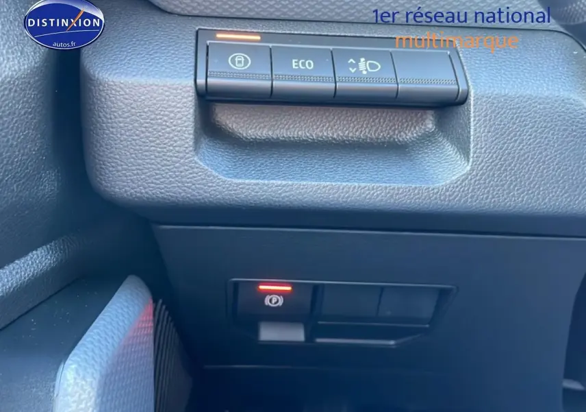 Gros plan sur les commandes du tableau de bord noir du Dacia Duster 1.2 mild hybrid 140 Journey, avec bouton ECO et frein à main électronique.
