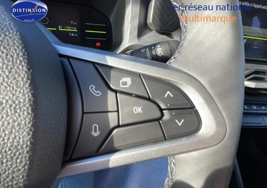 Gros plan sur les commandes multifonctions du volant du Dacia Duster noir, avec écran tactile et tableau de bord en arrière-plan.