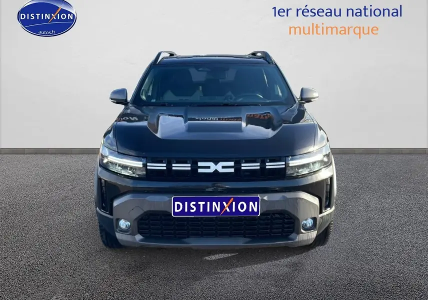 Vue frontale d'un Dacia Duster noir 2026 avec calandre distinctive et phares LED allumés.