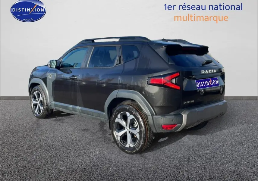 Vue 3/4 arrière droite du Dacia Duster noir 2026 avec jantes alu et barres de toit visibles.