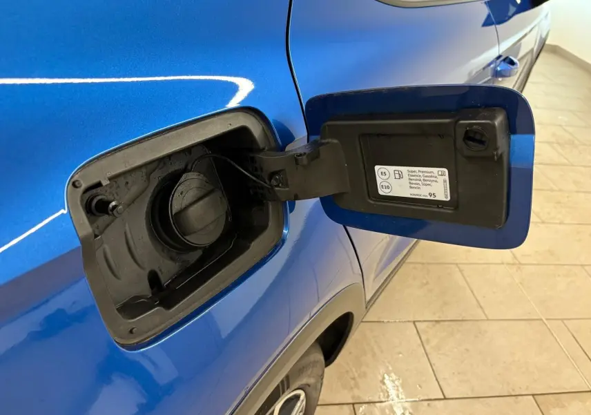 Vue rapprochée de la trappe à carburant ouverte côté gauche d’un SEAT Arona bleu saphir avec toit noir.