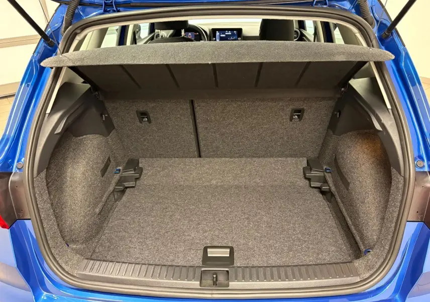 Coffre ouvert vu de l'arrière d'un SEAT Arona 2025 bleu saphir avec intérieur de coffre gris et toit noir visible.