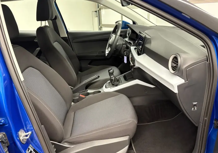 Vue intérieure côté conducteur du SEAT Arona bleu saphir, montrant les sièges tissu et la console centrale avec boîte manuelle.