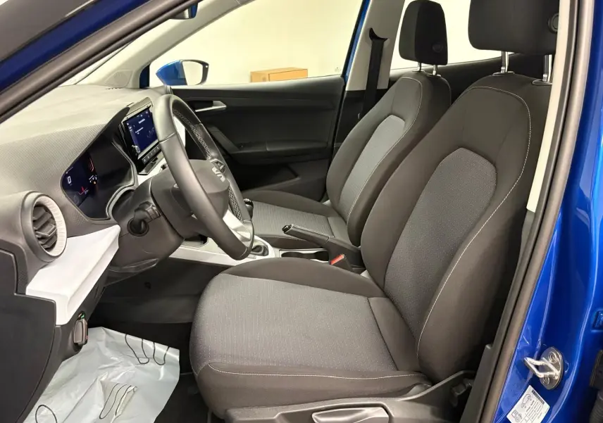 Vue intérieure côté conducteur du SEAT Arona 2025 bleu saphir, montrant les sièges avant et le tableau de bord.